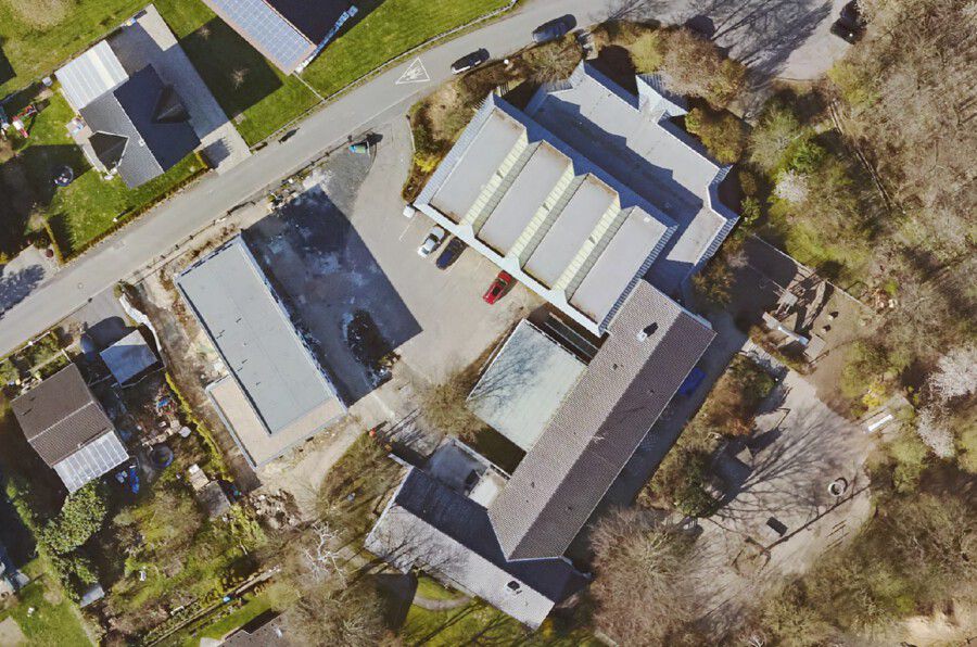 Diese Aufnahme zeigt die Paul-Gerhardt-Schule aus der Vogelperspektive. Der Planungsbereich für die Neugestaltung der Außenanlagen erstreckt sich auf den Park- und Vorßplatz in der Mitte der Gebäude sowie das Umfeld des OGS-Gebäudes (graues Flachdach links). (Luftbild: geoservice-kreis-unna.de)