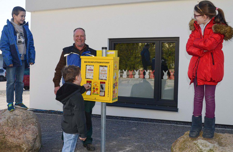 Das Foto zeigt Hausmeister Bernd Partmann mit Kindern der Notbetreuung der Paul-Gerhardt-Schule mit dem neuen Bienenfutter-Automat. Die offizielle Inbetriebnahme des Automaten muss wegen der Corona-Krise leider ausfallen. (Foto: privat)