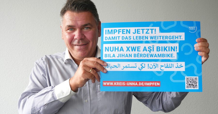 Landrat Mario Löhr zeigt den mehrsprachigen Flyer zur Kampagne "Impfen jetzt!". (Foto: Birgit Kalle - Kreis Unna)