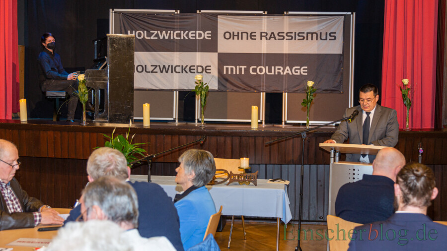 Holzwickedes stellvertretender Bürgermeister Peter Wehlack (r.) eröffnete die Gedenkveranstaltung. Kim Friehs (auf der Bühne li.) sorgte am Klavier für den musikalischen Rahmen zwischen den einzelnen Wortbeiträgen. (Foto: P. Gräber - Emscherblog)