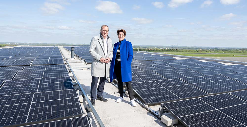 Ludger van Bebber, Geschäftsführer des Dortmunder Flughafens und Heike Heim, Vorsitzende der DEW21-Geschäftsführung, stehen auf dem Dach einer Luftfahrzeughalle mit der neu installierten Photovoltaik-Großanlage. (Foto: Frauke Schumann)